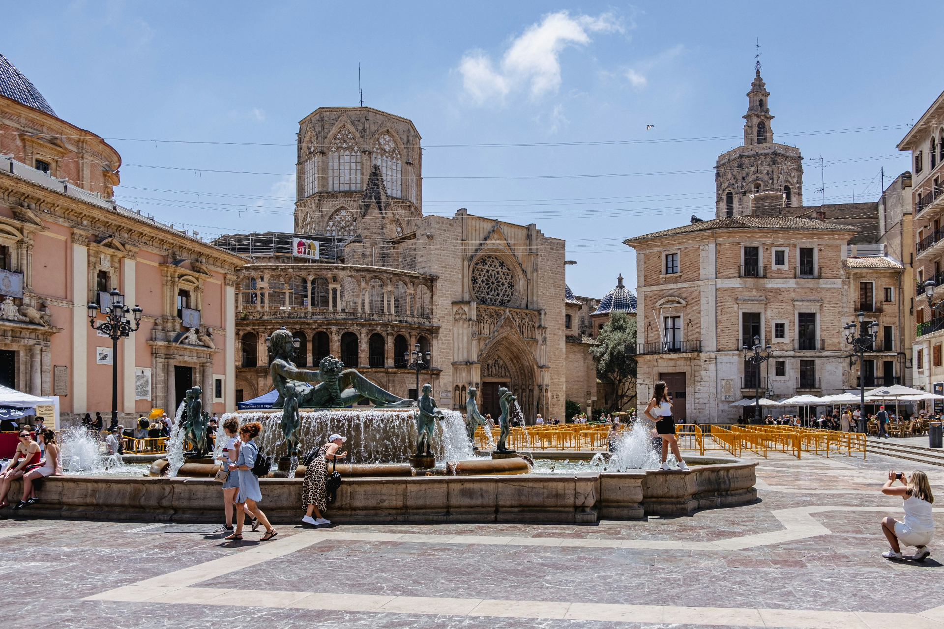 Plaza de la Virgen in Valencia with the cathedral, Turia fountain and visitors in the square on a sunny day